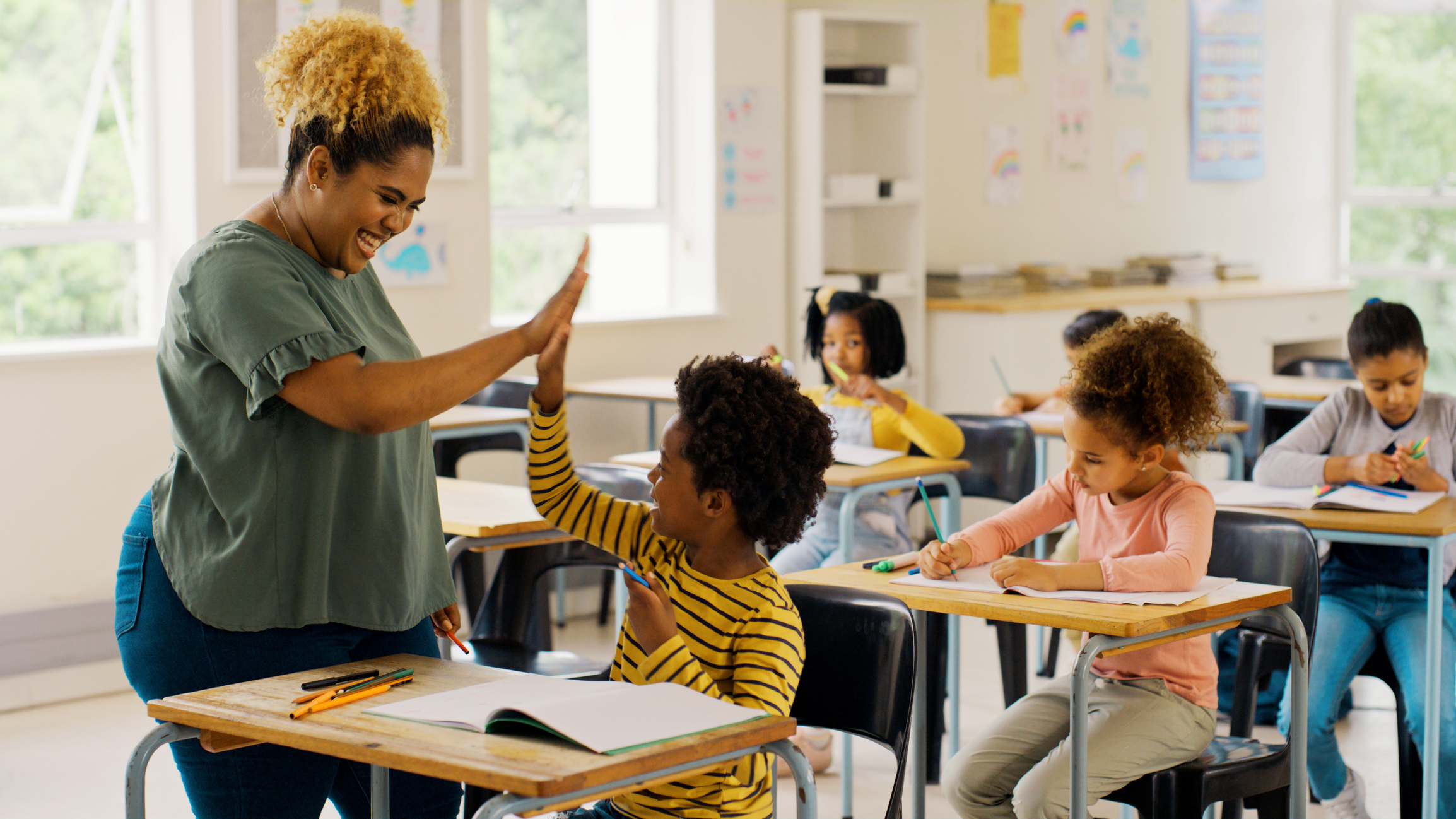 teacher high-fiving student at desk