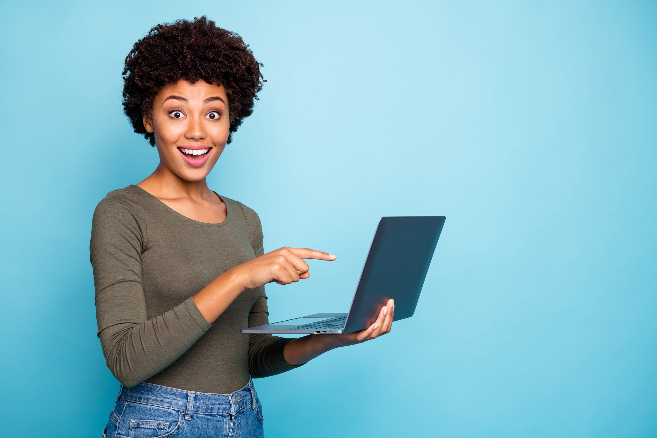 woman holding a laptop pointing at the screen and smiling